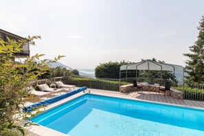Relax by the serene pool surrounded by lush gardens and a shaded seating area.