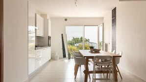Una cocina moderna con armarios blancos y una zona de comedor con mesa y sillas de madera.