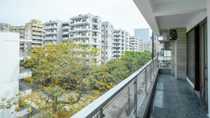 A balcony with a view of modern apartment buildings and trees. - FlxHo Uno - Golf Course Road (Gurugram)