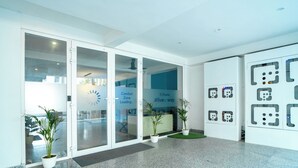 A modern reception area with glass doors, potted plants, and a sign indicating a comfort zone. - FlxHo Uno - Golf Course Road (Gurugram)
