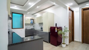 A modern kitchen with a marble countertop, built-in appliances, and a potted plant. - FlxHo Uno - Golf Course Road (Gurugram)