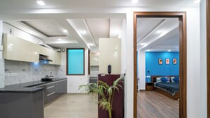 A modern apartment with a kitchen, a dining area, and a bedroom. - FlxHo Uno - Golf Course Road (Gurugram)