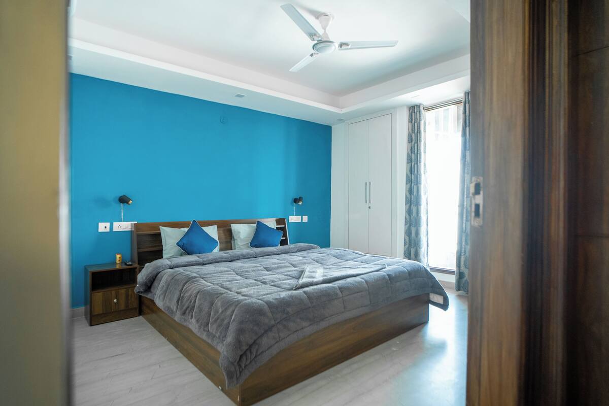 A bedroom with a large bed, a ceiling fan, and a window with curtains.