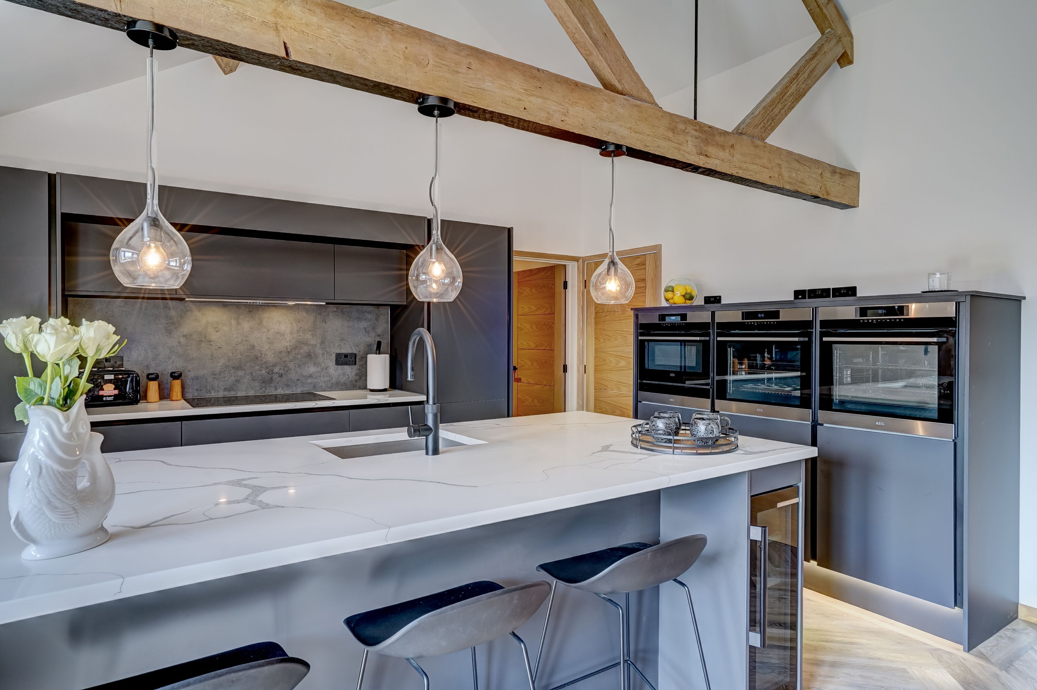 Une cuisine moderne dotée d’un grand îlot central, de luminaires suspendus et d’appareils électroménagers en acier inoxydable.