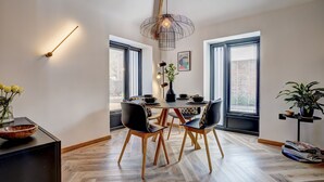 Uma sala de jantar moderna com piso de madeira em padrão herringbone, uma mesa redonda com cadeiras e uma luminária pendente.