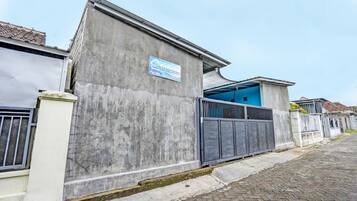 Un edificio in cemento con un portone blu, un ingresso con cancello e un cartello che indica un'attività commerciale denominata 'GANG SONGO'.