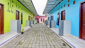 A corridor with tiled flooring, multiple doors, and potted plants. - Hotel O Gang Songo Syariah HomestayNearWisata Osing (Rogojampi)