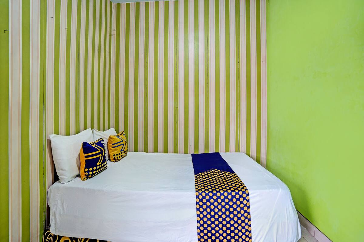 A bed with white bedding, blue and yellow pillows, and a blue and yellow patterned runner.