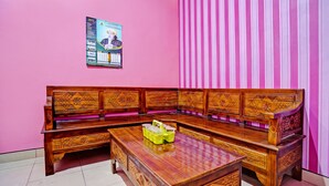 A traditional wooden sofa with intricate carvings, a matching wooden coffee table, and a pink-striped curtain in a room with a pink wall. - Hotel O Gang Songo Syariah HomestayNearWisata Osing (Rogojampi)