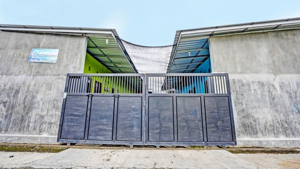 A gated entrance with a concrete wall and a metal gate. - Hotel O Gang Songo Syariah HomestayNearWisata Osing (Rogojampi)
