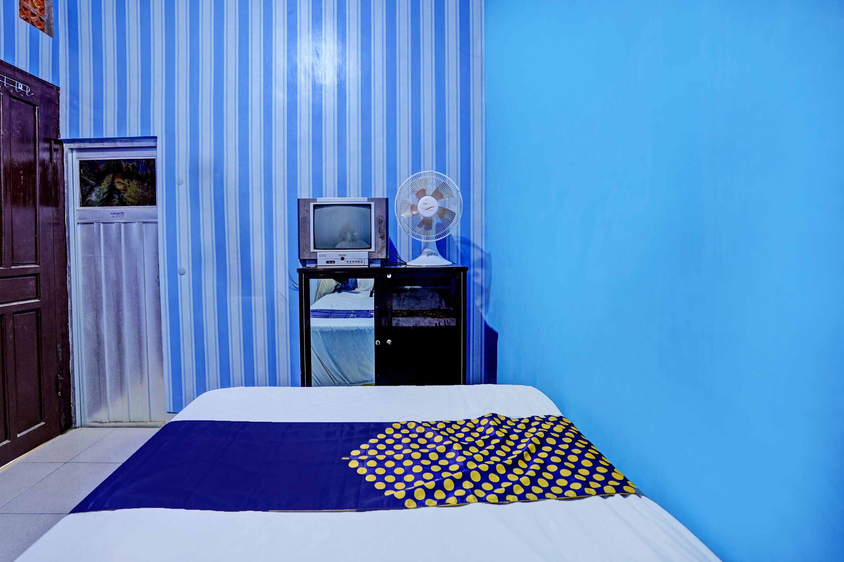 Une chambre avec un lit, une télévision et un ventilateur.