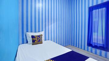 Una habitación de hotel con cama, papel tapiz a rayas y una ventana con cortinas.