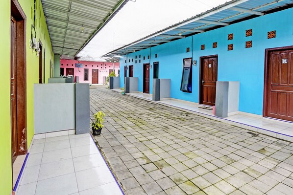 A courtyard with tiled flooring, a green building, and a blue building with multiple doors and windows.