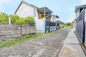 Una estrecha calle adoquinada flanqueada por edificios residenciales con porche cubierto y valla de madera.