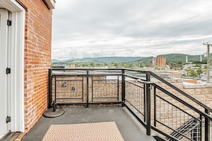 Un balcon donnant sur un paysage urbain, un mur de briques et un portail en métal.