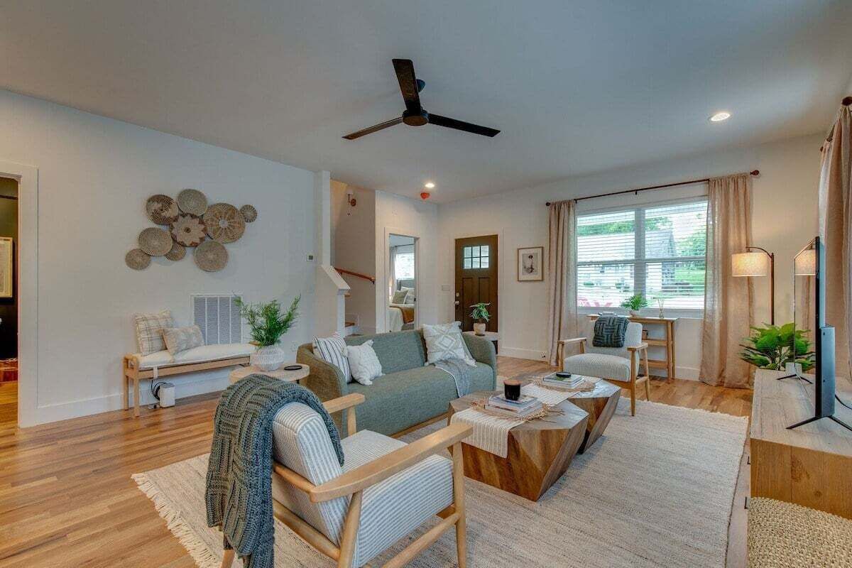 A spacious living room with a sofa, armchairs, a coffee table, and a ceiling fan.