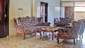 A room with a large, ornate sofa and matching armchairs, a wooden coffee table, and a tiled floor. - Hotel O Badar Guest House Syariah (Bandar Lampung)