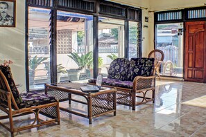 Una habitación con muebles de mimbre, un ordenador portátil sobre una mesa y vistas a través de amplios ventanales.
