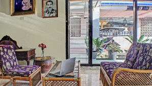 A room with wicker furniture, a laptop on a small table, and a view through an open door to the outside. - Hotel O Badar Guest House Syariah (Bandar Lampung)
