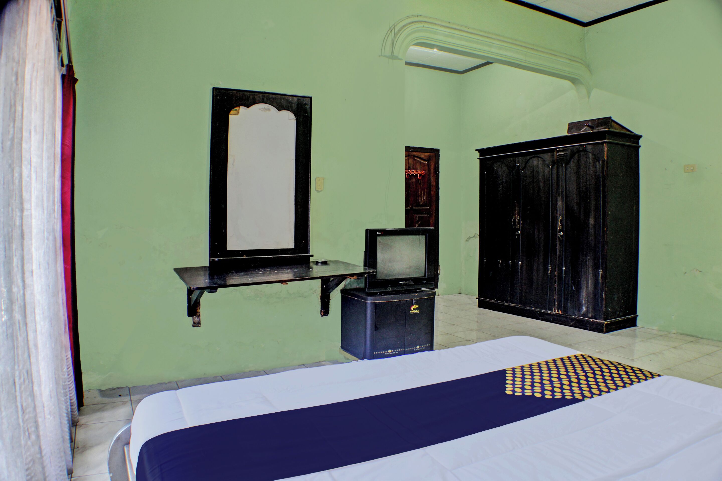 A room with a bed, a television, a wardrobe, and a mirror.