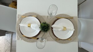 Ein Esstisch, gedeckt mit zwei Tellern, Besteck und einem Glas.