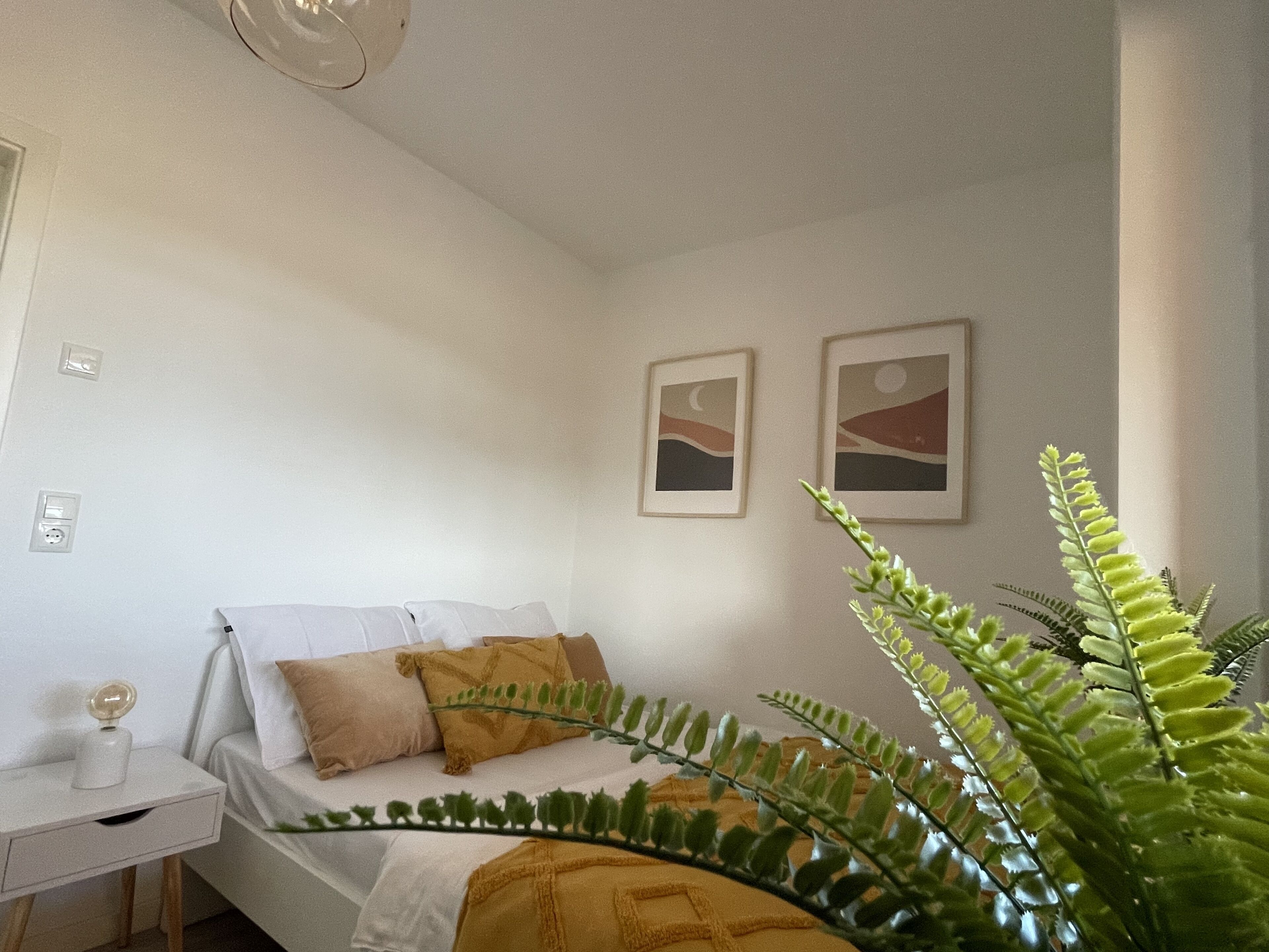 Un dormitorio con cama, mesita de noche y una planta.