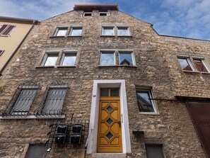 A stone building with a wooden door, multiple windows, and a balcony with metal railings. - homie stay badgasse - am Main mit Dachterrasse (Ochsenfurt)
