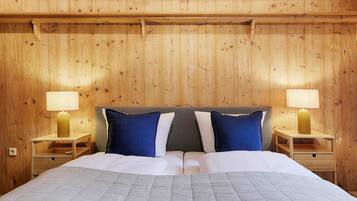 A wooden-paneled room with a bed, two bedside tables, and two lamps.