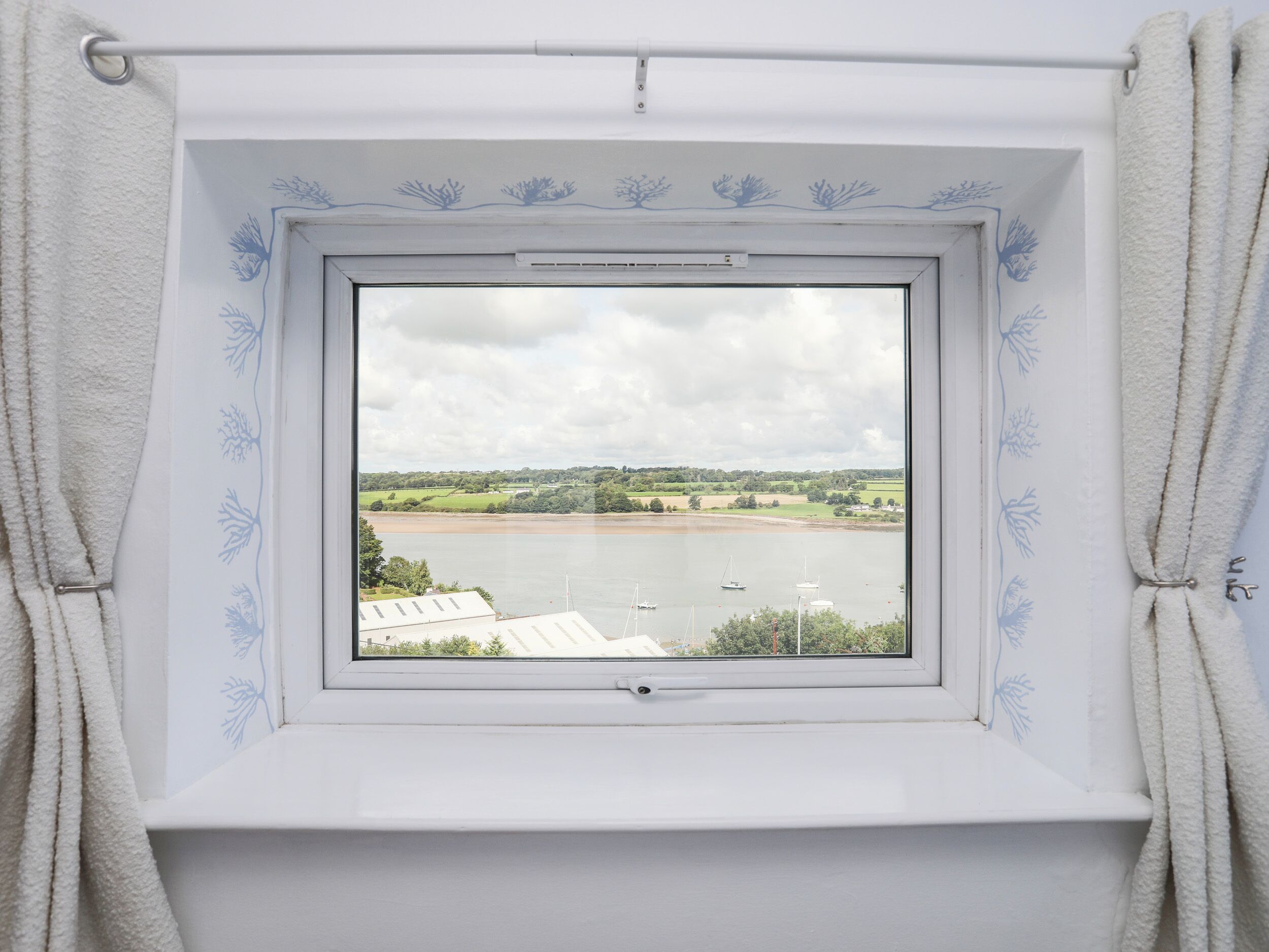 A window with a view of a river and surrounding landscape.