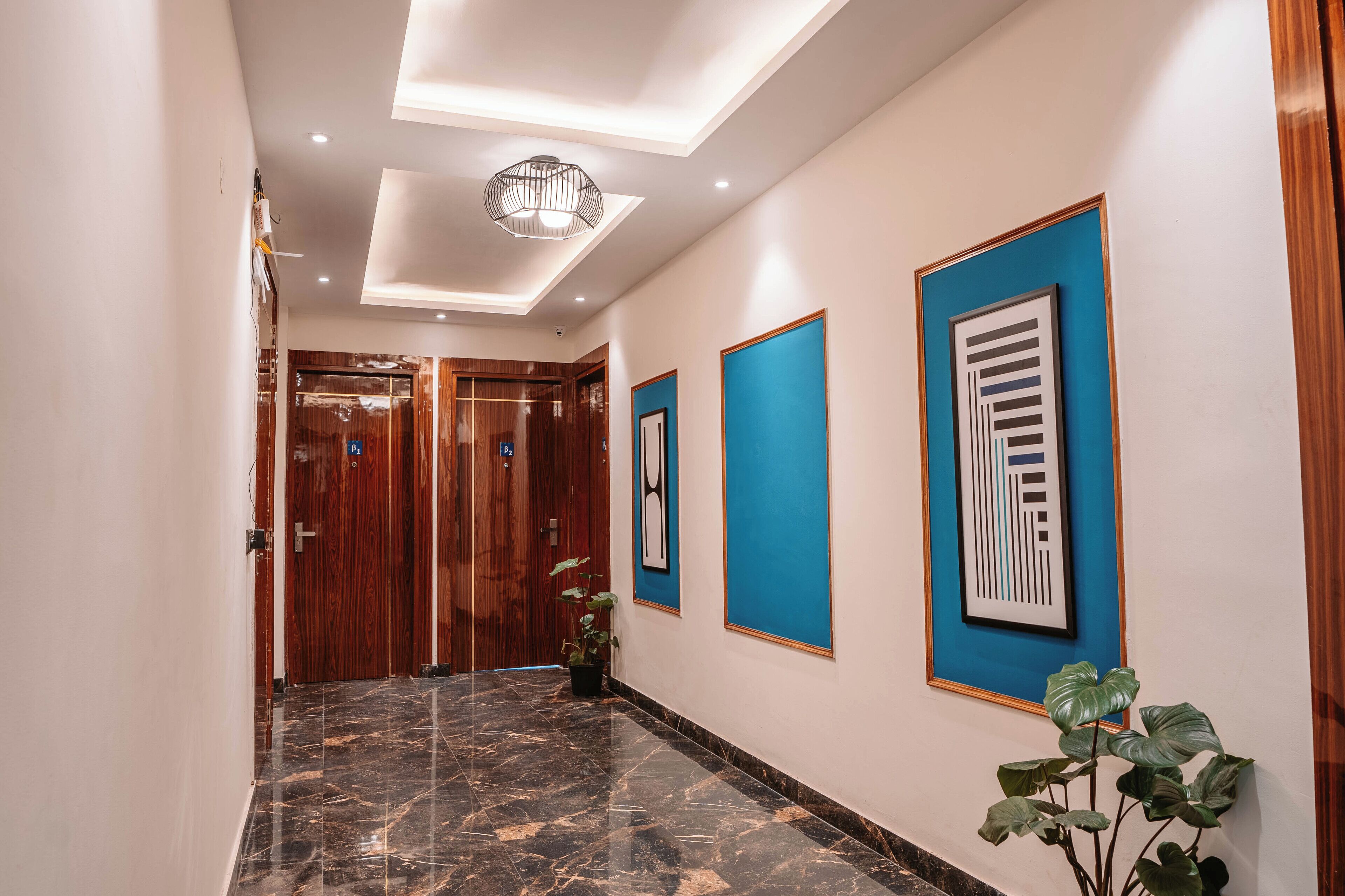 A hallway with a polished marble floor, wooden doors, and framed artwork on the walls.