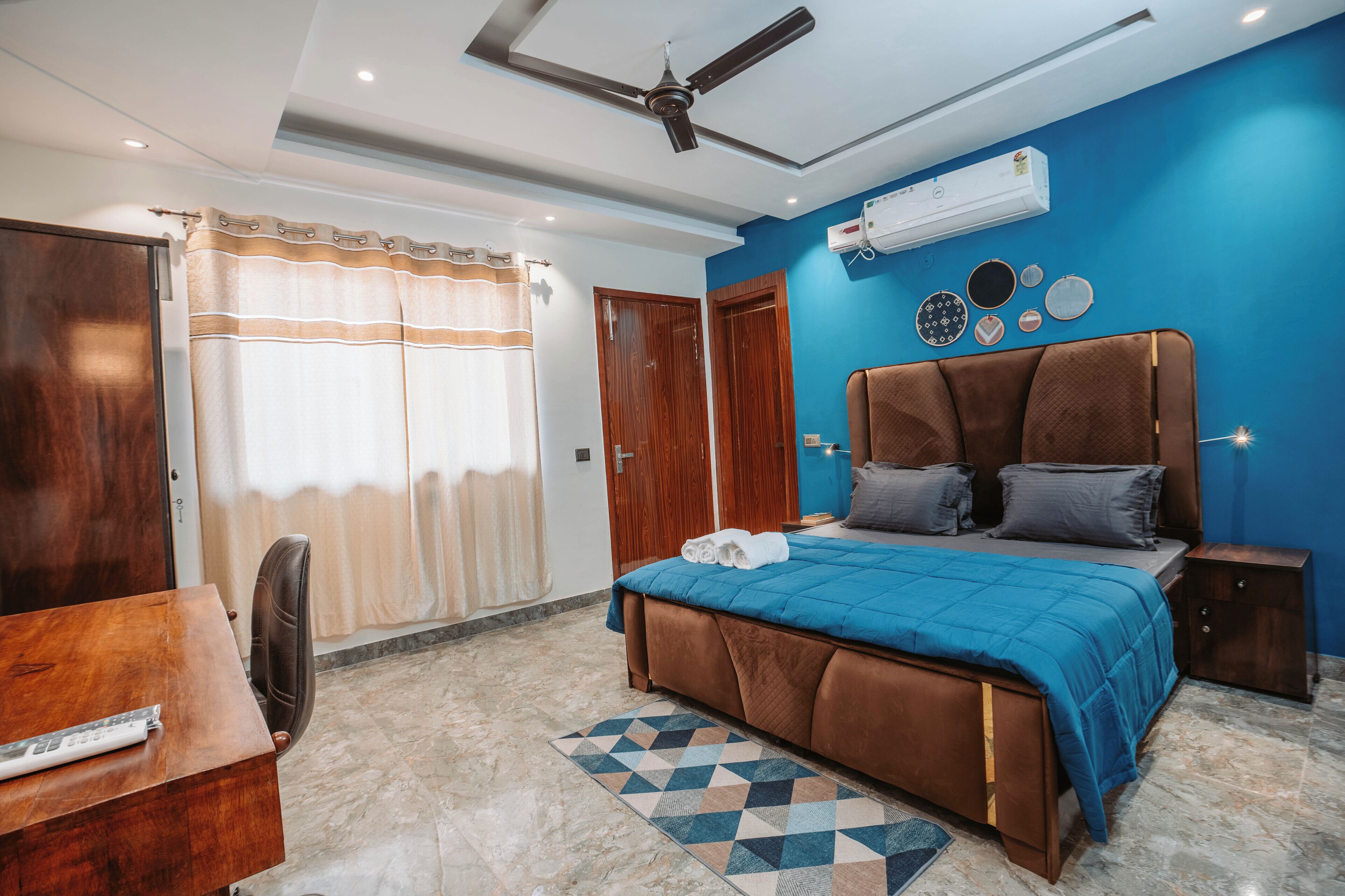 A bedroom with a bed, a desk, a chair, a ceiling fan, and an air conditioning unit.