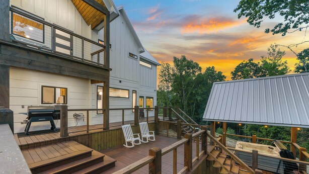 A two-story house with a deck, outdoor seating, and a hot tub.