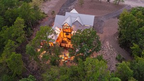 A large house with a spacious deck and a fire pit surrounded by chairs.