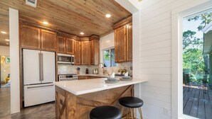 A kitchen with wooden cabinets, a white countertop, and two black bar stools.
