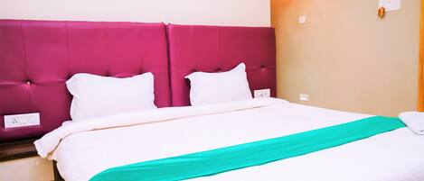 A bed with a white and teal bedspread, a pink headboard, and white pillows.