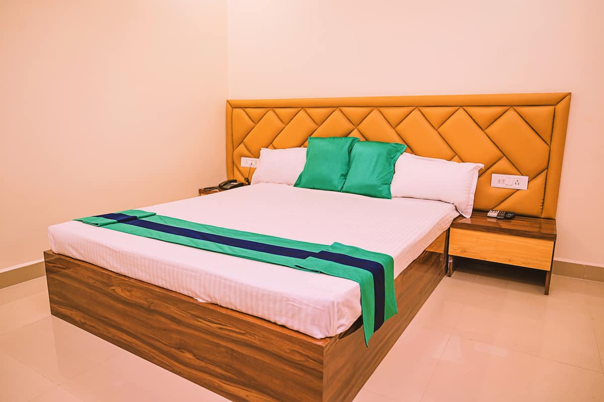 A neatly made bed with a wooden headboard, a green and blue bedspread, and a white pillow.
