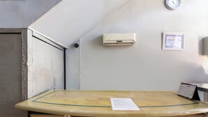Quarto com escrivaninha, ar condicionado, relógio e um certificado emoldurado na parede.