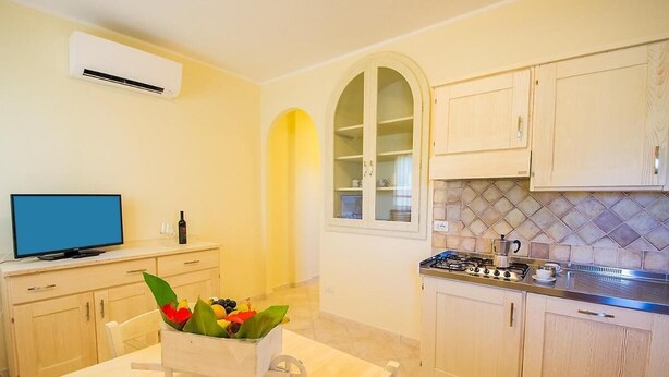 A compact kitchen with a stove, cabinets, and a TV. - Relaxing Le Residenze del Maria Rosaria No2213 (Orosei)