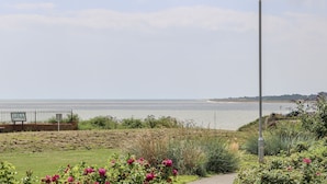 Un sentier menant à une plage, avec un lampadaire et un panneau indicateur.
