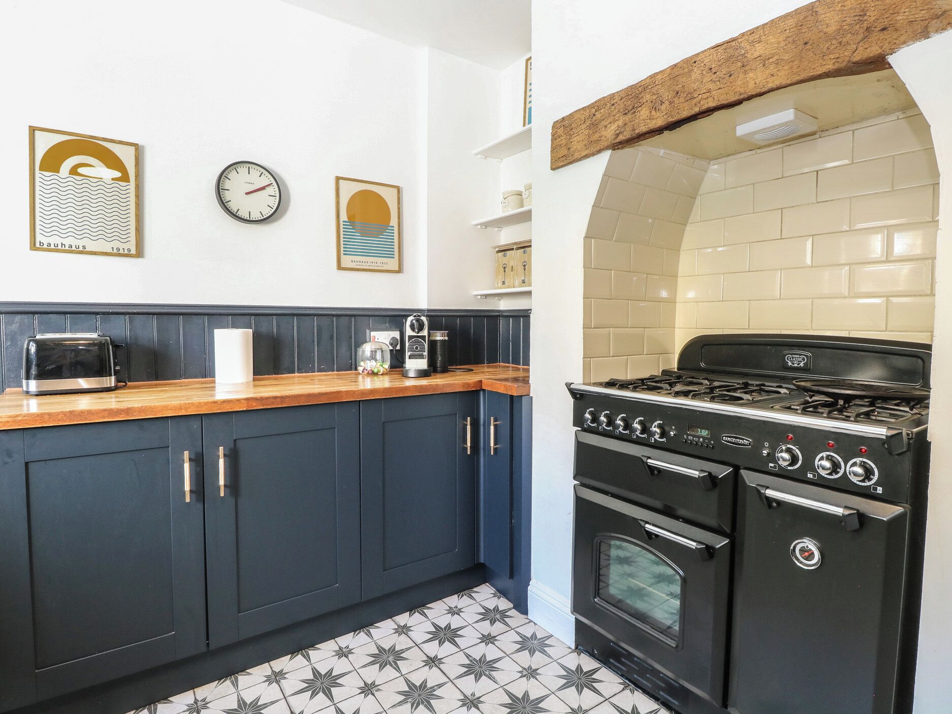 A kitchen with dark blue cabinets, a wooden countertop, a classic stove, and a tiled backsplash.