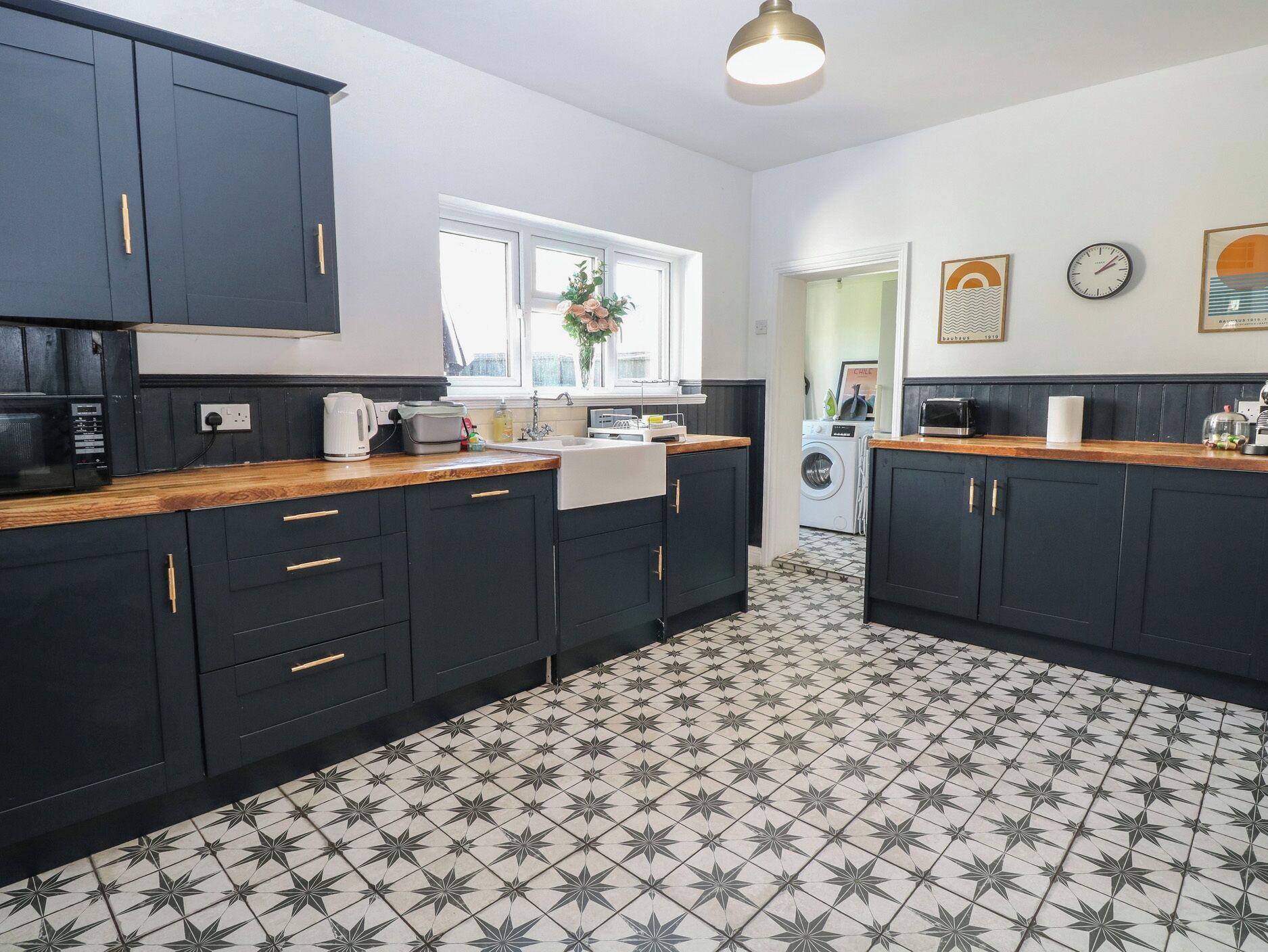 A modern kitchen with dark cabinetry, a tiled floor, and a window with a view.