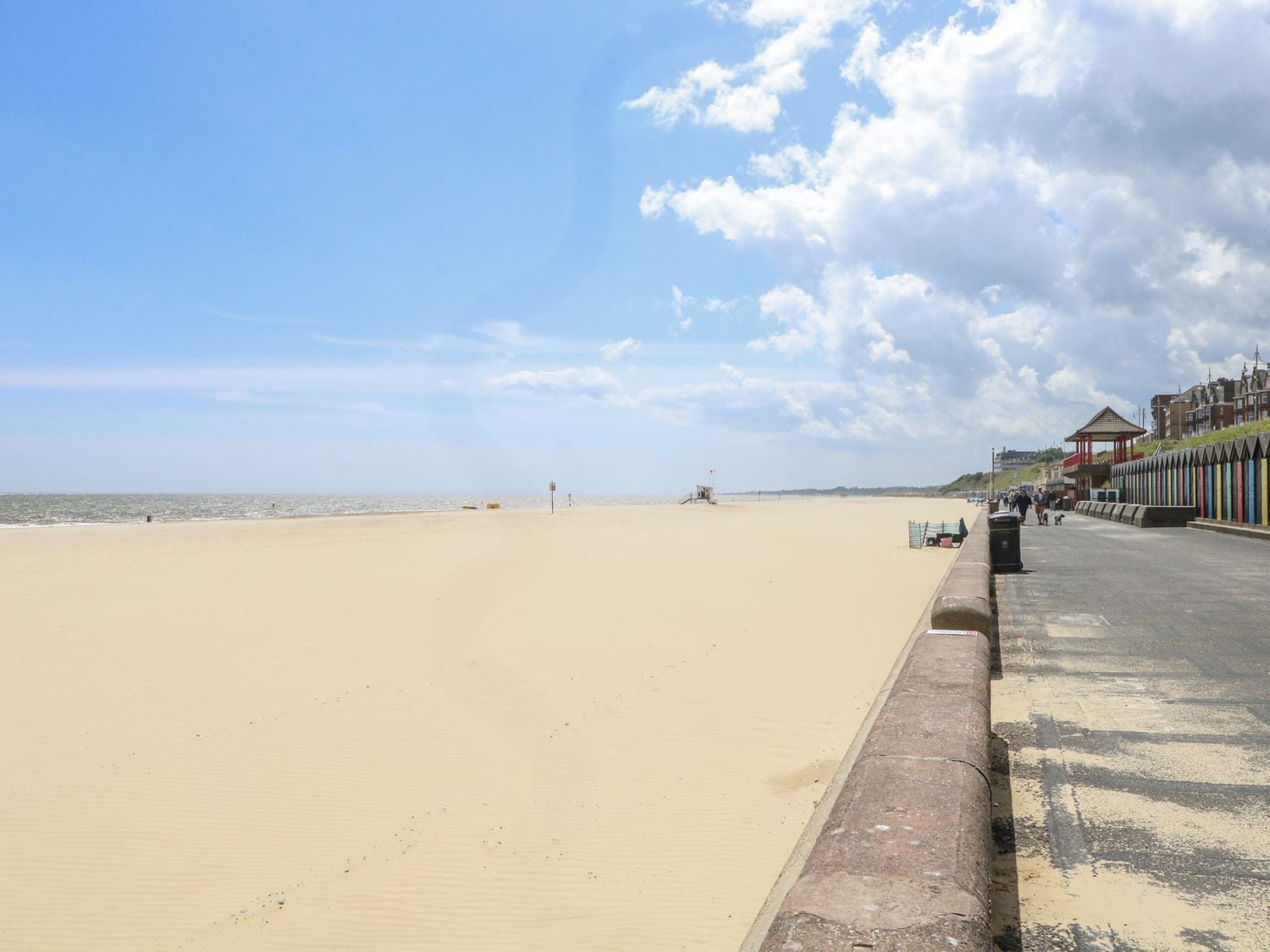 A beach with a promenade, a lifeguard tower, and a row of colorful buildings.
