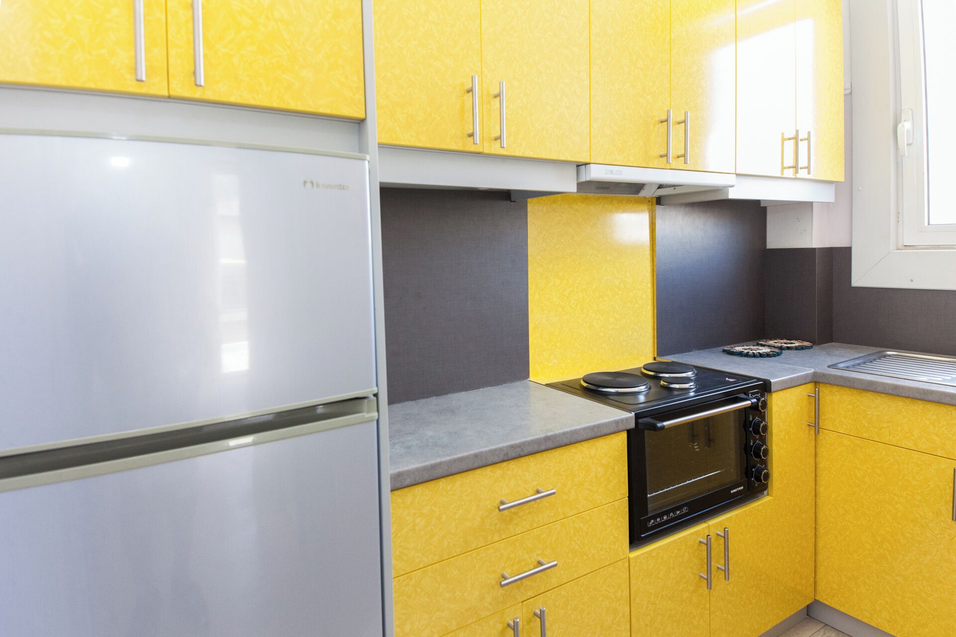 A kitchen with yellow cabinets, a white refrigerator, and a black oven.