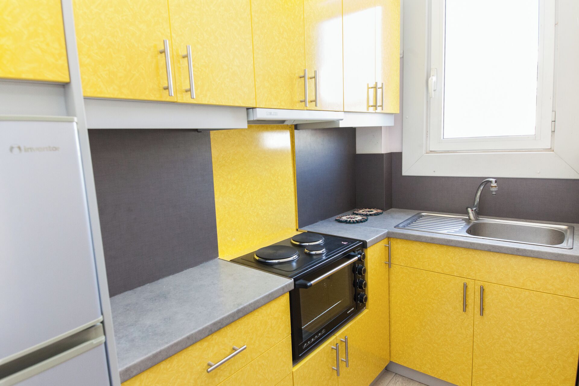 A compact kitchen with yellow cabinets, a black stove, and a sink.
