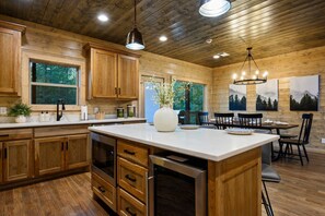 A spacious kitchen with wooden cabinets, a large island, and a dining area with a chandelier.