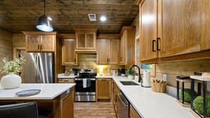Une cuisine avec des meubles en bois, des appareils électroménagers en acier inoxydable et un plan de travail blanc.