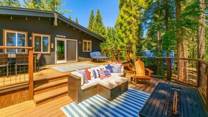 Une terrasse dotée de mobilier d’extérieur, d’un foyer et offrant une vue sur la forêt environnante.