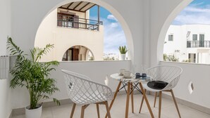 A balcony with white chairs, a table, and a potted plant. - Golden Bird's (Naxos)