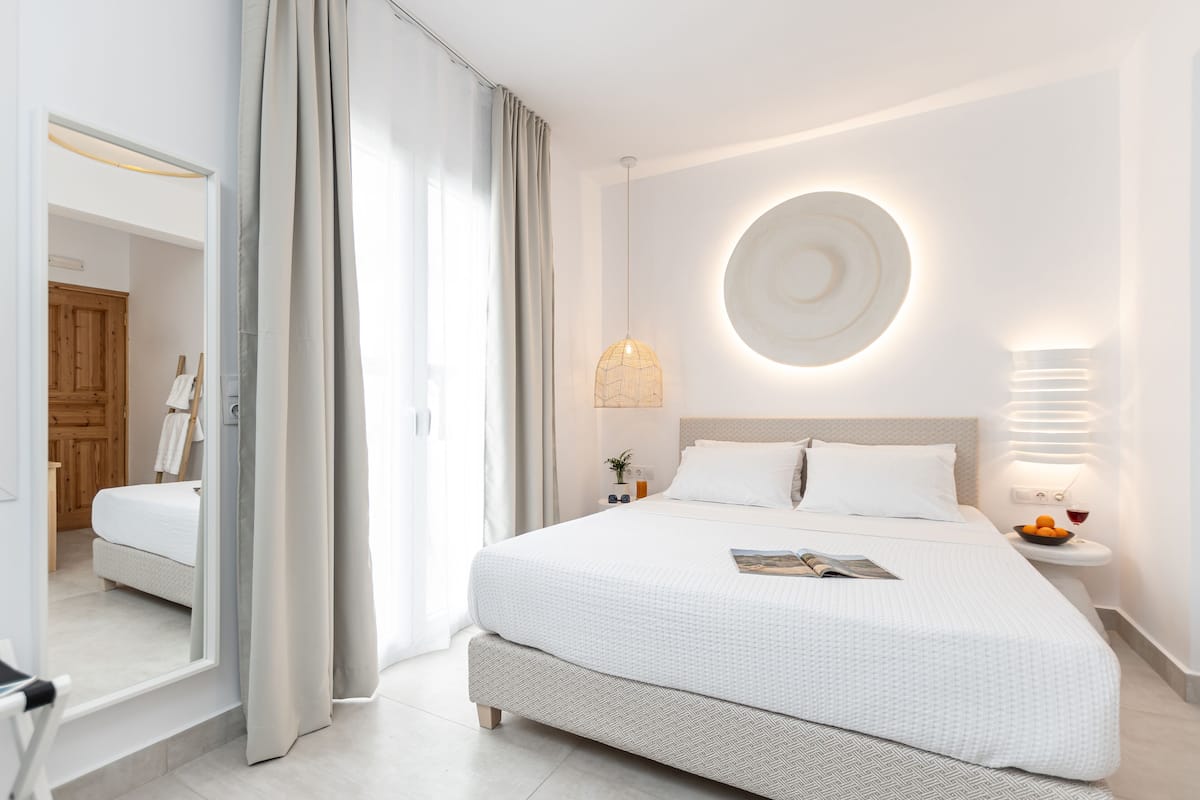 A modern bedroom with a large bed, a bedside table with a lamp, and a circular wall decoration.
