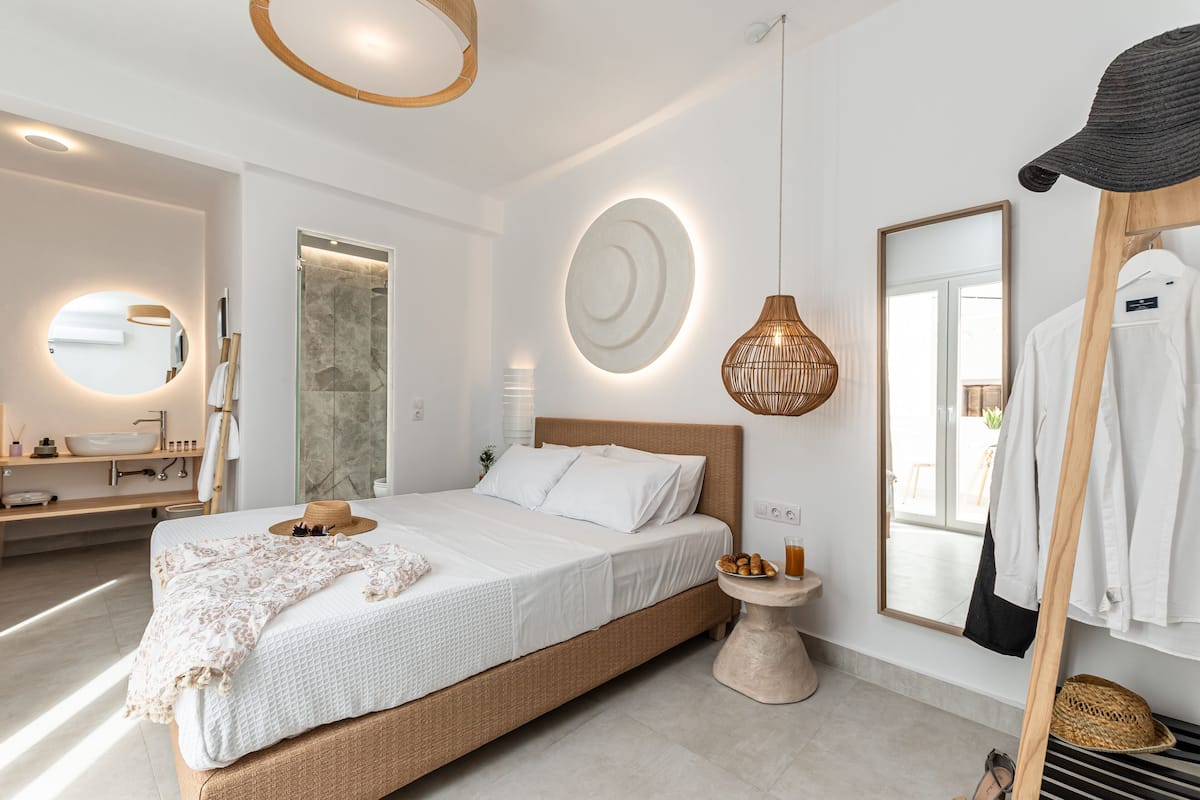 A modern bedroom with a large bed, a bedside table, a hanging light fixture, and a mirror on the wall.